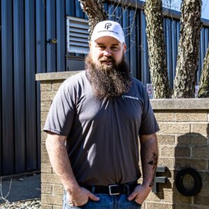 John Butler, Plant Manager and Machine Operator at Fostermation, standing in a manufacturing facility representing precision machining and production leadership.